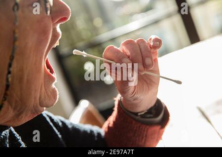 close up of a senior woman using a home test coronavirus mouth swab Stock Photo