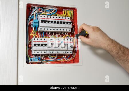 Electrician installing panel with electric meter in apartment of customer Stock Photo