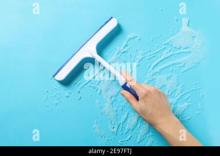 Female hand hold window сleaning squeegee on blue background with foam Stock Photo