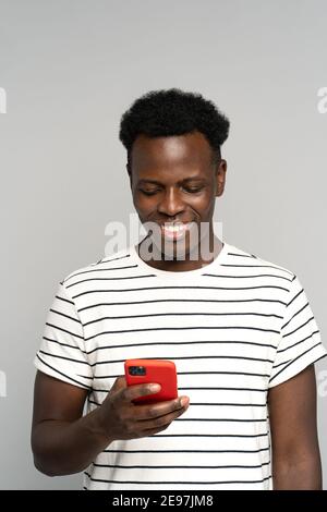 Happy African millennial man in glasses, holding mobile phone, isolated on studio grey background Stock Photo