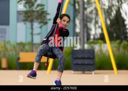 The little girl on the bungee jumping for kids outdoor. Stock Photo