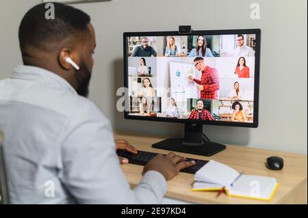 Brainstorm, online video meeting, virtual conference with multi ethnic coworkers, employee, colleagues. View over shoulder of an African guy on a Stock Photo