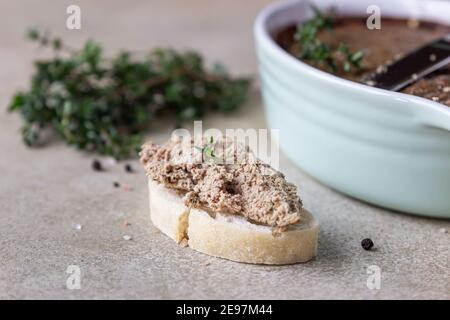 Ciabatta with chicken or turkey liver pate with thyme, concrete background. Selective focus. Stock Photo