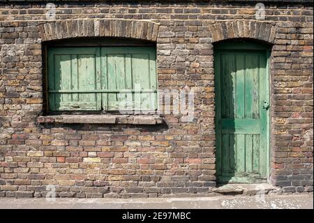 Old Green wooden door and window with wooden shutters on Victorian building Stock Photo