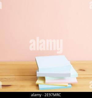 Stack of colorful memo pad, sticky notes on wooden desk. Pink background, copy space. Work and study place Stock Photo