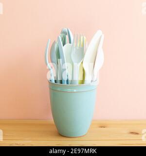 Kitchen utensils, Fork knife spoon in holder on wooden table. Pink background Stock Photo