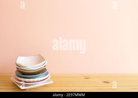 Stack of colorful dishes on wooden table. Pink background Stock Photo