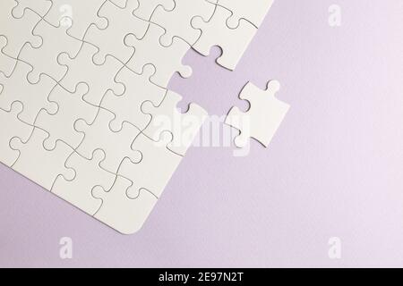 Set of white puzzle pieces and last one piece on purple background. top view Stock Photo