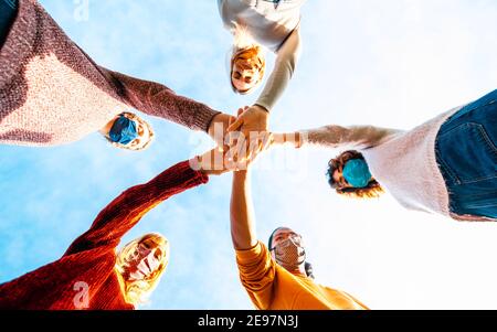 College students teamwork stacking hands - New normal lifestyle concept with people covered by face mask helping each other Stock Photo
