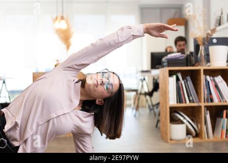 Hispanic female worker having a break to stretch and relax in the office. Stock Photo