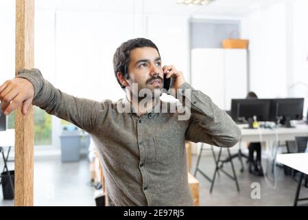 Confident hispanic man with mustache talking on the phone at the workplace. Stock Photo