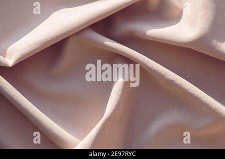 Beige linen fabric with pleats. Abstract neutral textile background. Selective focus. Close up. Stock Photo