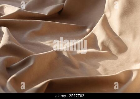 Beige linen fabric with pleats. Abstract neutral textile background. Selective focus. Close up. Stock Photo