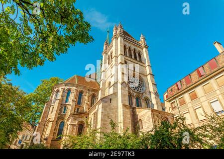 Bottom view of romanesque lateral facade, bell tower and gothic spire of Saint-Pierre Cathedral in a sunny day. Church in old historic town of Geneva Stock Photo