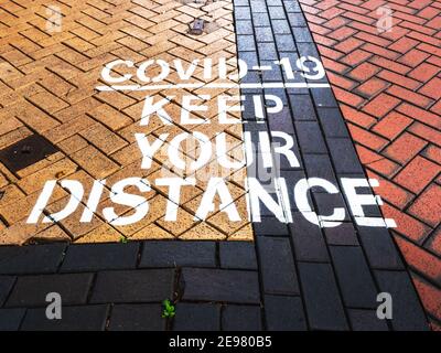 Close up of Covid-19 distancing warning sign painted on UK pedestrian area. New Street, Birmingham, West Midlands. Stock Photo