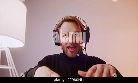 Portrait of young caucasian man with headphones laughing speaking and typing on the laptop keyboard. High quality photo Stock Photo