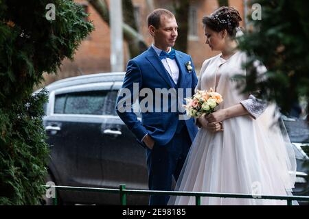 two newlyweds on a wedding walk in winter, lovers happily hug and gently kiss, two adults on a date Stock Photo