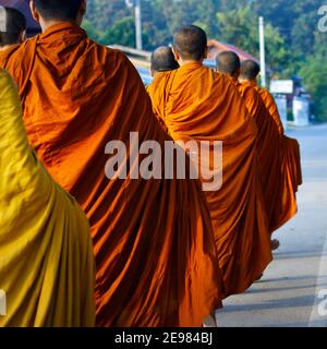 monks dressing orange robe during reception of alms, around buddhist temple Stock Photo