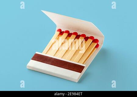 Open matchbox book, full of matches with red heads. Isolated on blue background with shadow Stock Photo