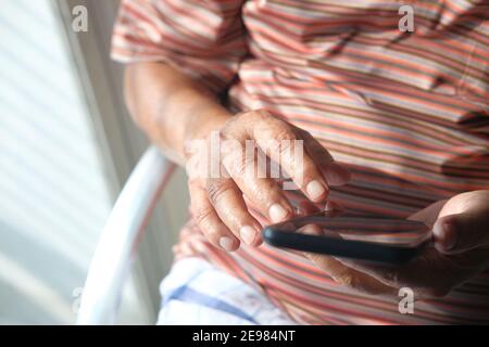Close up of senior man hand using smart phone at home  Stock Photo