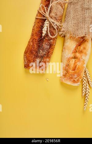 Top view of two baguette bread on a yellow surface.  Concept of homemade bread, small bakery, natural farm products, local food,  domestic production. Stock Photo