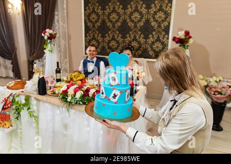 the bride and groom together cut the wedding cake, a traditional treat for guests in the restaurant, a wedding ceremony and happiness for the family Stock Photo
