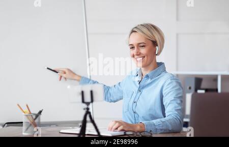 Online school. Female teacher pointing at blank blackboard, teaching lesson on web, explaining new material to students Stock Photo