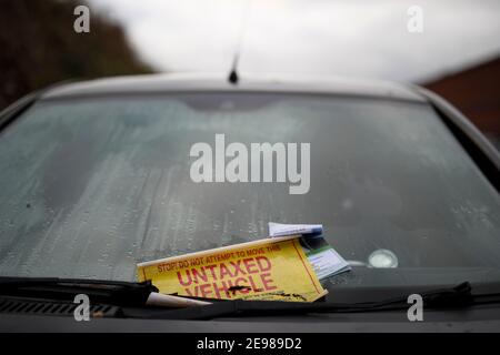 Loughborough, Leicestershire, UK. 3rd February 2021. A warning sticker peels from a Fiat Punto car immobilised by a DVLA clamp for having no road tax. Stock Photo