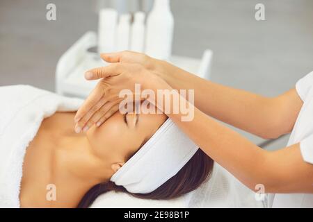 Masseur making professional manual relaxing rejuvenating massage for young womans face Stock Photo