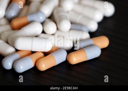 Pills on a dark wooden table, variety of medications in capsules. Background for pharmacy, antibiotics, vitamins Stock Photo