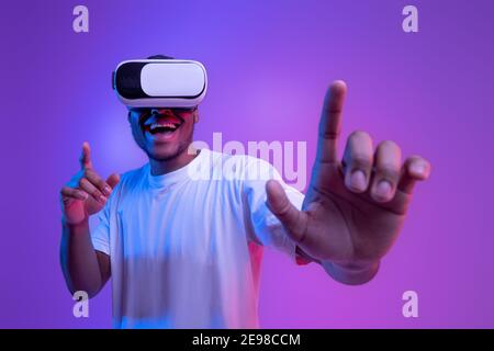 Augmented reality world. Excited black guy in vr glasses, touching ...