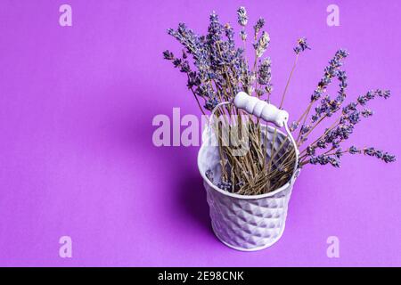 Bunch of dried lavender flowers in bucket on a lilac background. Fragrant flowers, indispensable ingredient, play for text, flat lay Stock Photo