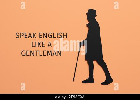 the text speak english like a gentleman and the silhouette of an elegant man, wearing hat and using a walking cane, cutout on a black paperboard, on a Stock Photo