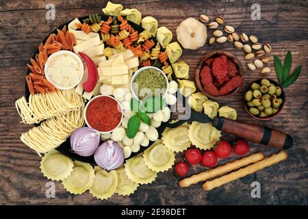 Large collection of Italian pasta & health food ingredients on an old cast iron pan & rustic wood background. Low cholesterol healthy diet. food. Stock Photo