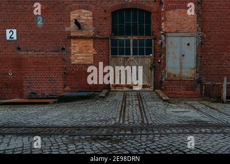 An old rusty gate of an old warehouse, old brick warehouse, brick facade and an old gate Stock Photo