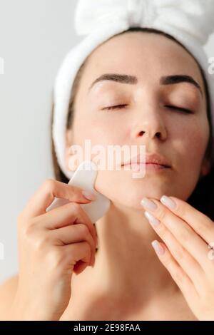 portrait of woman using Gouache Scraper Massager over face skin Stock Photo