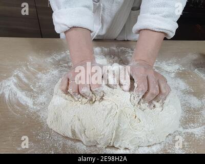 housewife kneads dough in the kitchen, housewife makes homemade cakes. Stock Photo