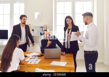 Group of young company employees discussing work matters and analyzing sales data Stock Photo