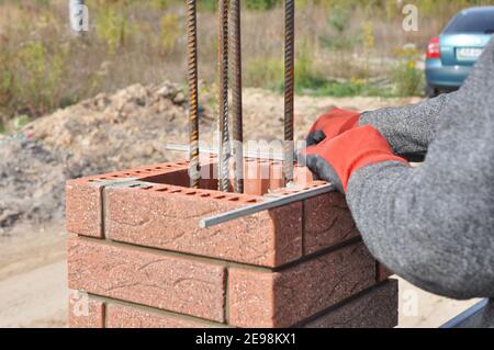 Closeup on brick laying blocks correctly on fence brick column. Laying brick to build a mailbox enclosure, or building a brick column with rebar. Stock Photo