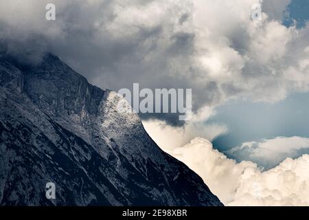Storm cloud over a mountain flank with a spot of sunlight on the rocks Stock Photo