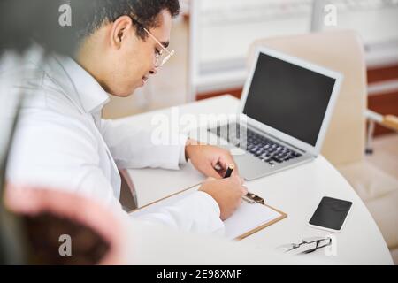 Experienced optometrist focused on writing an eyeglass prescription Stock Photo