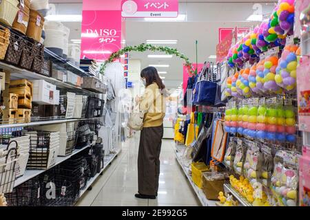 A woman wearing a facemask as a preventive measure against the spread of  Coronavirus (COVID-19) shops at Daiso 100 Yen Store in Tokyo. Daiso is one  of the biggest 100 Yen shop chains in Japan with a range of more than  100,000 items ranging from