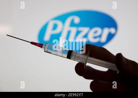 OXFORD, UK - February 2020: A covid vaccine syringe in front of the pfizer logo Stock Photo
