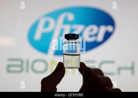 OXFORD, UK - February 2020: A covid vaccine vial in front of the pfizer logo Stock Photo