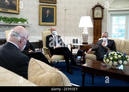 President Joe Biden, center, wears a protective mask while meeting with U.S. Vice President Kamala Harris, not pictured, Senate Majority Leader Chuck Schumer (D-N.Y.), right, and fellow Democratic Senators to discuss the American Rescue Plan in the Oval Office of the White House in Washington, DC on Wednesday, February 3, 2021.           Pool photo by Stefani Reynolds/UPI Stock Photo