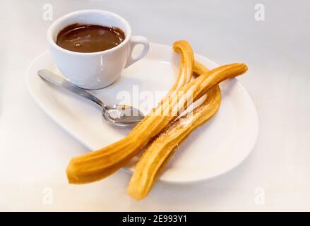 Plate of fried Spanish Churros topped with sugar and hot chocolate sauce as served in traditional gastronomy Stock Photo