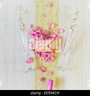 Romantic festive still life with two glasses, a bottle of rose wine , a gift box and rose petals on white background. Valentine's Day. Little moments Stock Photo