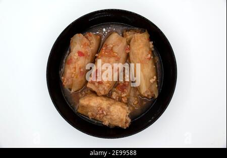 A dish of cabbage rolls in a black plate, which is minced meat with boiled rice, wrapped in cabbage leaves. Stock Photo