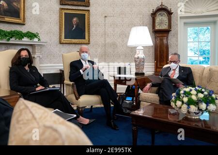 President Joe Biden, center, wears a protective mask while meeting with U.S. Vice President Kamala Harris, left, Senate Majority Leader Chuck Schumer (D-N.Y.), right, and Democratic Senators to discuss the American Rescue Plan in the Oval Office of the White House in Washington on Wednesday, February 3, 2021. Credit: Stefani Reynolds / Pool via CNP | usage worldwide Stock Photo