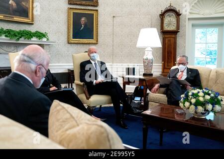 President Joe Biden, center, wears a protective mask while meeting with U.S. Vice President Kamala Harris, not pictured, Senate Majority Leader Chuck Schumer (D-N.Y.), right, and fellow Democratic Senators to discuss the American Rescue Plan in the Oval Office of the White House in Washington on Wednesday, February 3, 2021. Credit: Stefani Reynolds / Pool via CNP | usage worldwide Stock Photo